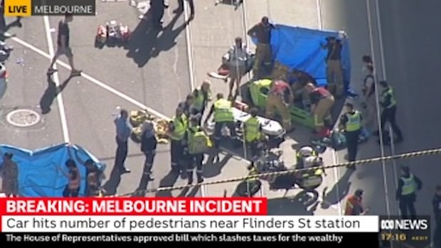 Emergency services tend to pedestrians outside of Flinders Street Station. 