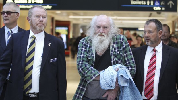 Colin Michael Newey is escorted through Sydney Airport by police after being extradited from South Australia in July.