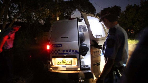 Terrorism arrests: A man is put into a police vehicle in Marsfield.