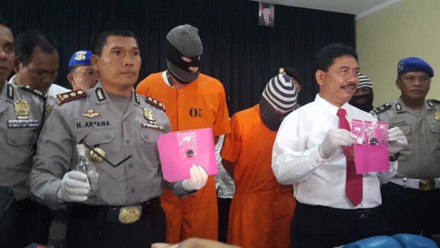 Police with Australian Giuseppe Serafino (in orange prison clothes, right) and Briton David Fox, after their arrest in October last year.
