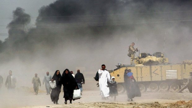 The war: Iraqis pass by a British tank as they flee Basra in 2003.