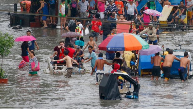 Residents in Cavite in the Philippines wade through the flood water following heavy rains in September this year.