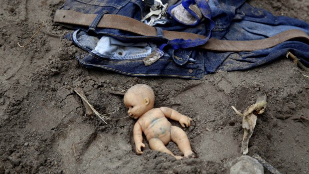 A doll and clothing lie in the mud as rescue workers continue to search the site of the deadly mudslide in Cambray, a suburb of Santa Catarina Pinula.