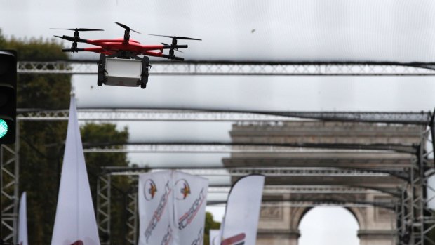 A drone holds a box during an exhibition flight in Paris.