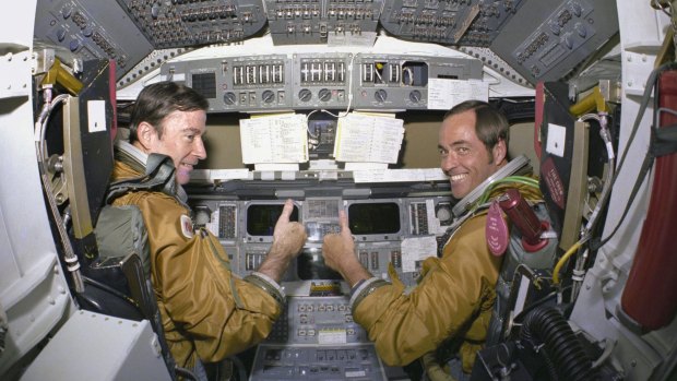 Commander John Young (left) and Pilot Robert Crippen, take a break from their intensive training schedule to pose for pictures on the flight deck of the space shuttle Columbia at the Kennedy Space Center in 1980.
