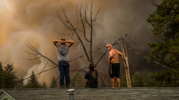 Daniel Ravera, left, and Bill Stafford, right, stand on a neighbour's home to watch the fire move towards their property in Sheep Ranch, California, on Sunday.