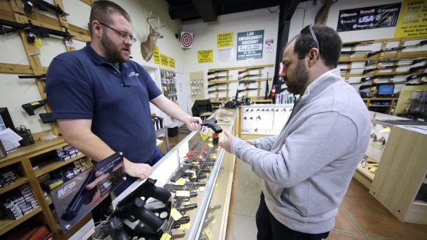 Mike Howse, left, helps David Foley as he shops for a handgun in Spring, Texas.