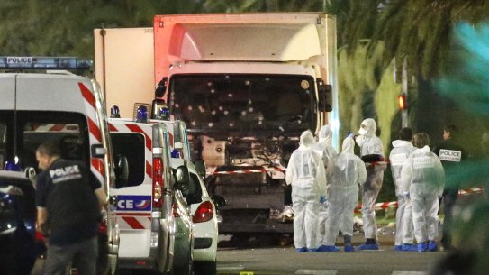 French police forces and forensic officers stand next to a truck that ran into a crowd in Nice.