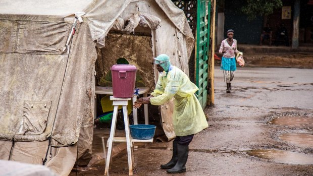 A health worker cleans his hands before entering an Ebola screening tent in Kenema, Sierra Leone.