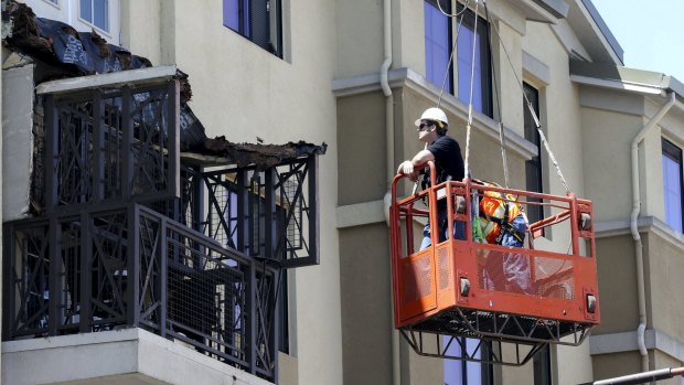 Workmen examine the damage at the scene.