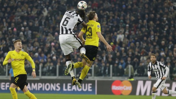 Juventus' Paul Pogba and Dortmund's Marcel Schmelzer, right, jump for the ball.