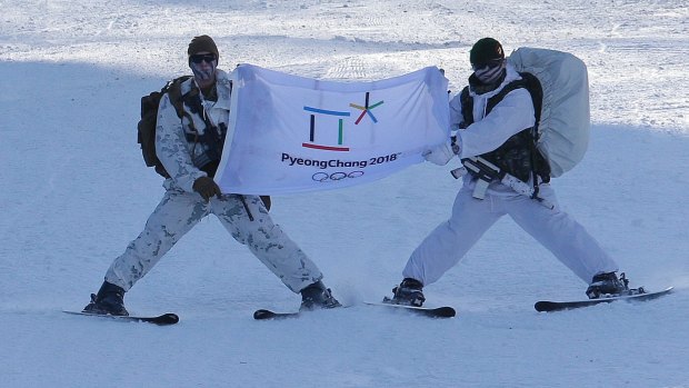 A South Korean, right, and US Marine from 3-Marine Expeditionary Force from Okinawa, Japan, ski with a flag of the 2018 Pyeongchang Winter Olympic Games during their joint military winter exercise in Pyeongchang.