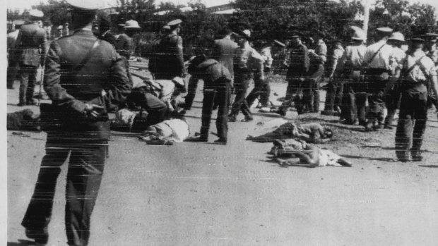 Police move among bodies outside the Sharpville police station after police opened fire with sten guns and rifles on 12,000 stone-throwing protesters in South Africa in 1960.