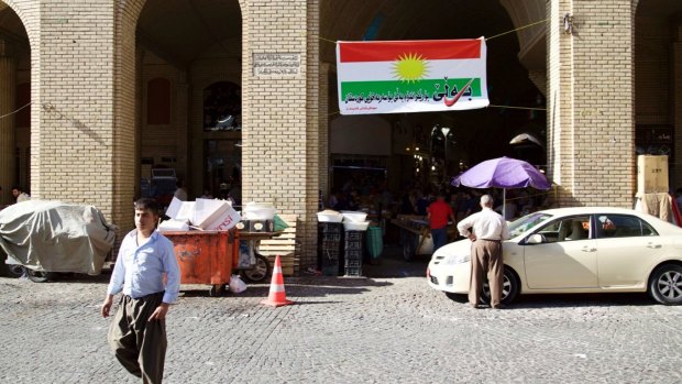 A man walks past a campaign poster printed on a Kurdish flag urging people to vote yes in the upcoming poll in Irbil, Iraq. 