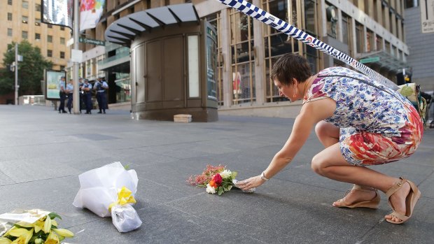 A woman cries as she leaves flowers to pay her respects at Martin Place. 