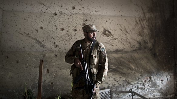 A Pakistani army officer stands guard inside the school in Peshawar that was attacked last week.