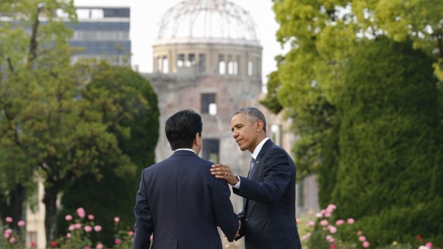 President Barack Obama and Japanese Prime Minister Shinzo Abe talk with Hiroshima's atomic memorial in the background.