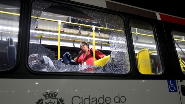 A member of the media stands near a shattered window on the bus.