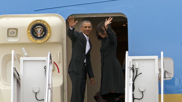 President Barack Obama, accompanied by first lady Michelle Obama, waves while boarding Air Force One before their departure  at Andrews Air Force Base, Maryland. 