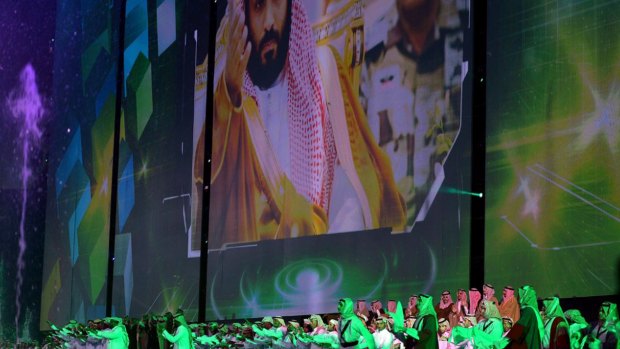 Saudi men perform under a giant screen showing an image of Saudi Crown Prince Mohammed Bin Salman during National Day ceremonies in Riyadh, Saudi Arabia. 
