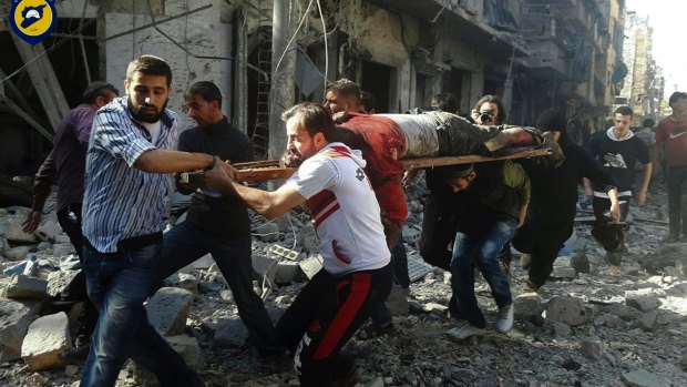 Syrians carry a victim after air strikes by government helicopters on the Aleppo neighbourhood of Mashhad on Tuesday.