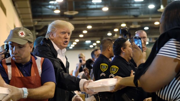 President Donald Trump passes out food and meets people affected by Hurricane Harvey during a visit to the NRG Center in Houston.