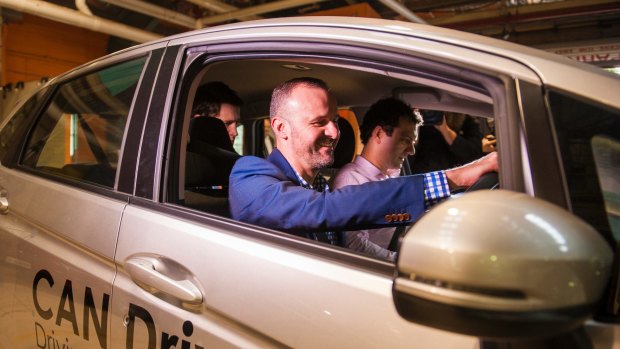 Chief Minister Andrew Barr takes the wheel in a self-driving car at the announcement of a new trial in Canberra.