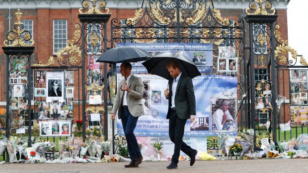 Britain's Prince William, left, and Prince Harry visit tributes to their late mother placed on the gates of Kensington Palace.