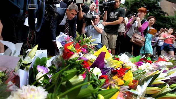NSW Premier Mike Baird lays flowers at Martin Place after the siege where three people died.