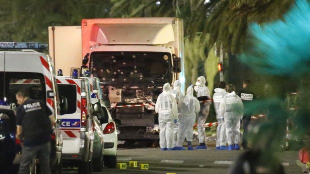 French police forces and forensic officers stand next to a truck that ran into a crowd in Nice.