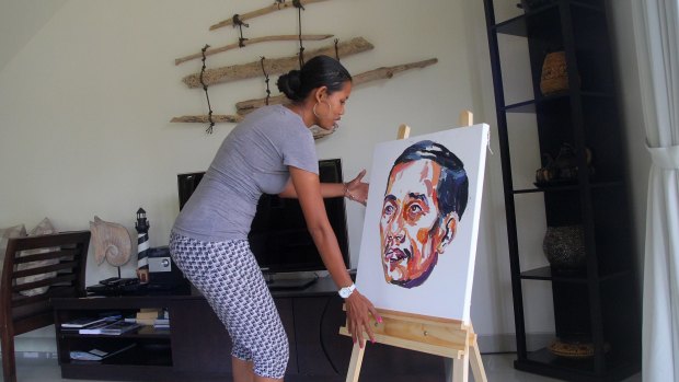 A woman places the painting of Joko Widodo painted by Bali Nine member Myuran Sukumaran on an easel.