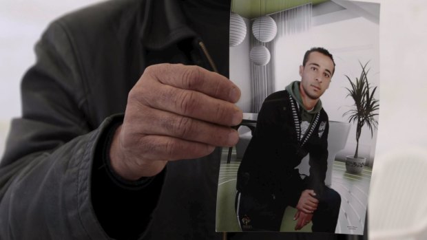 The cousin of Yassine al-Abidi, who gunned down 20 foreign tourists at Tunisia's Bardo museum, shows a photo of Yassine during an interview in Tunis.