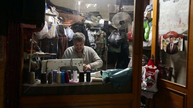Bunkered down: Life goes on for this Damascus tailor despite the war on the streets outside. 