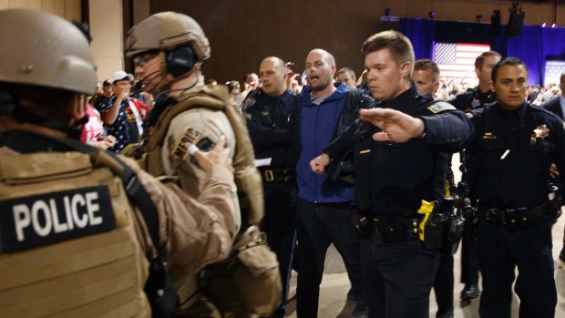 A man escorted by law enforcement officers moments after Republican presidential candidate Donald Trump was rushed offstage.