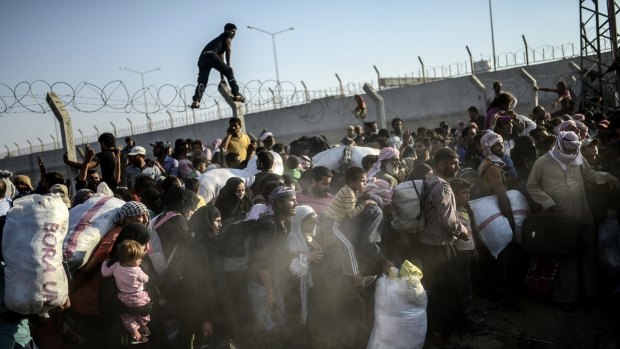 Acts of desperation as Syrians flee fighting between Kurds and Islamic State near the Turkish border on Sunday. 