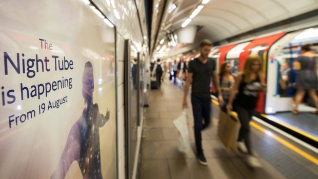 Passengers pass an advert for the night tube on a platform at Oxford Circus underground station in London.