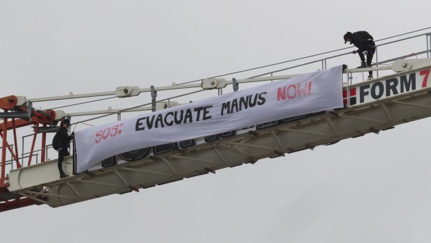 Protesters unfurl a banner on a crane at Flemington race track.