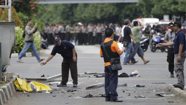 Police officers examine debris at the site of an explosion in Jakarta.