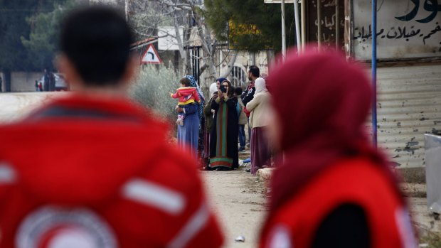 Members of the Syrian Red Crescent stand near aid vehicles loaded with food and other supplies in the besieged town of Madaya.