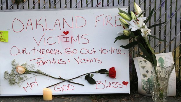 Signs and flowers adorn a fence near the site of a warehouse fire in Oakland, California. 