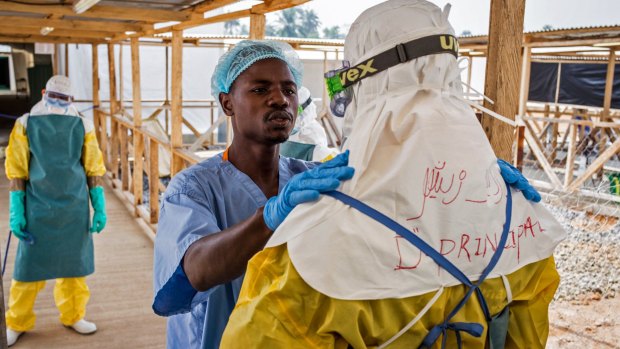 A health care worker prepares a colleague's protective gear at an Ebola virus clinic operated by the International Medical Corps in Makeni, Sierra Leone. 