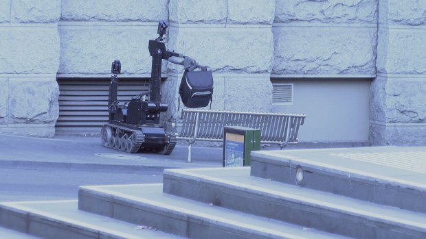A bomb disposal robot picks up the padded bag left outside the Batman's Hill on Collins hotel.