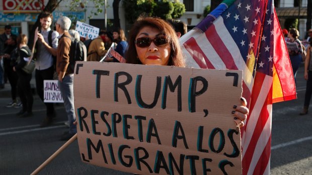 A woman holds a sign that reads in Spanish "Trump, respect migrants" in Mexico on the day of his inauguration.