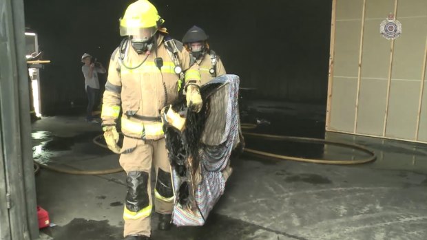 Firefighters remove a mattress burnt in a reconstruction of the house fire at Morayfield.