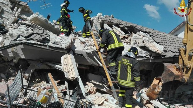 Firefighters search through debris in Amatrice.
