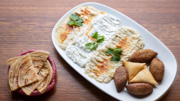 Mixed appetiser platter with dips and samboosa pastries.