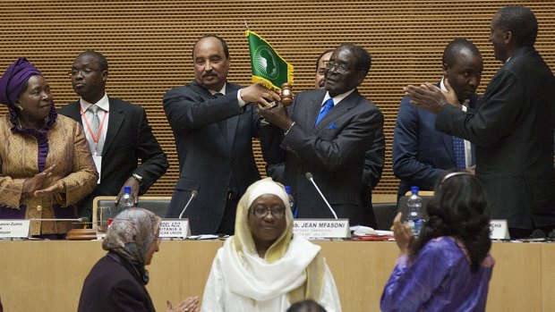 Zimbabwe President Robert Mugabe is handed the African Union flag in Addis Ababa.