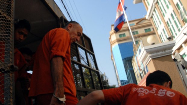 Australian teacher George Moussallie (left) enters a Phnom Penh court in handcuffs last year.