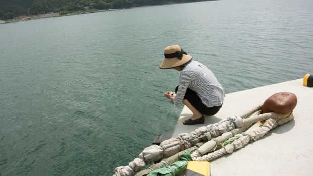 Hiromi Narita, in Konori, dropping a lunch box into the water for her daughter, Emi.