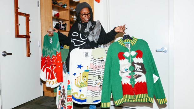 Whoopi Goldberg with the collection of 'ugly Christmas sweaters' she designed.